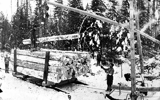 Men loading logs onto wooden sled, ca. 1910.