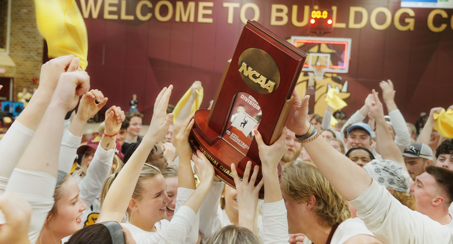 A crowd of hands reach for a NCAA trophy after a recent women's basketball win